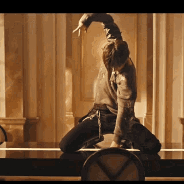 a man is kneeling down with his arms outstretched in a room with columns