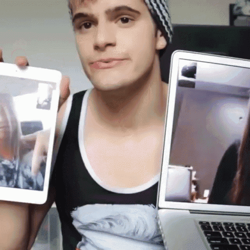 a man holding a tablet and a laptop with a woman on the screen