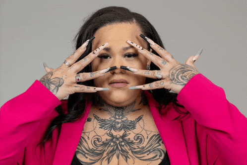 a woman with a tattoo on her chest covering her face with her nails