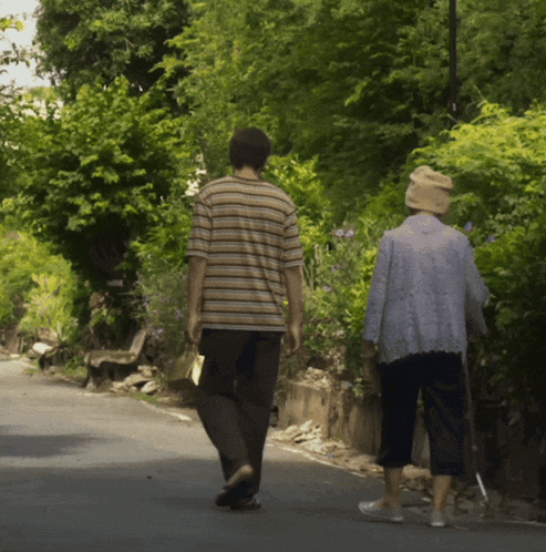 a man and a woman walking down a road with trees in the background