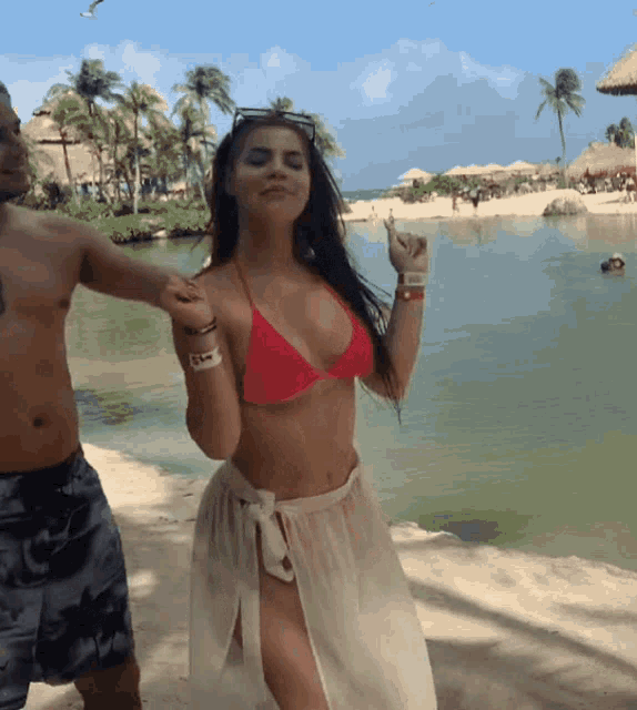 a woman in a red bikini is being held by a man on the beach