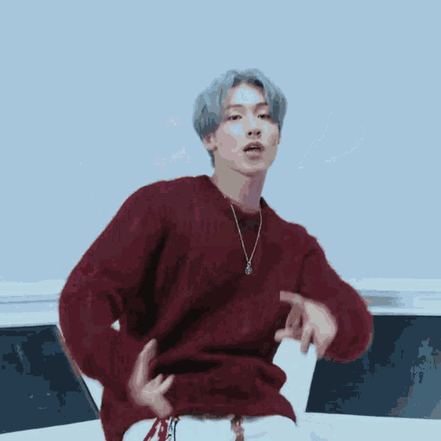 a man in a red sweater is making a heart with his hands