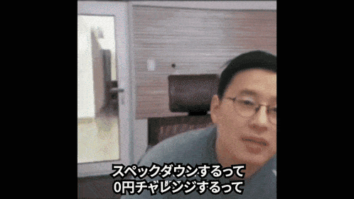 a man wearing glasses is talking in a room with foreign writing on the bottom