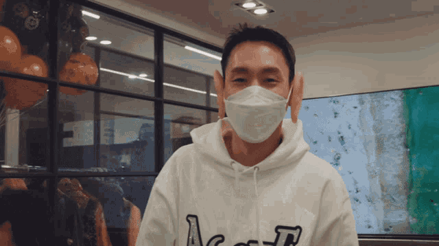 a man wearing a mask and a white hoodie with the letter a on it