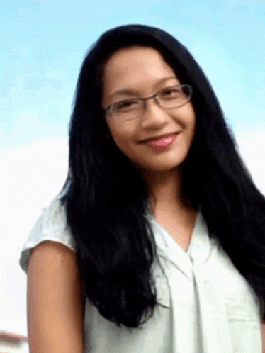 a woman with long black hair wearing glasses and a white shirt