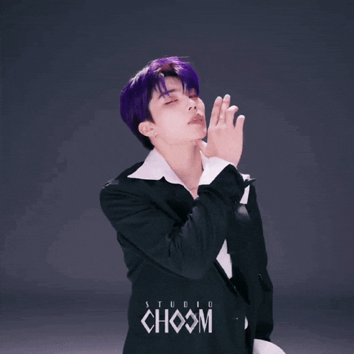 a young man with purple hair is wearing a black suit