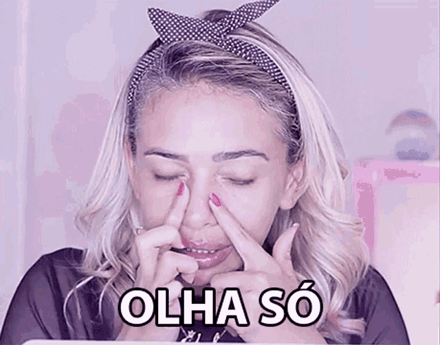 a woman is touching her nose with her fingers and the words olha so are above her .