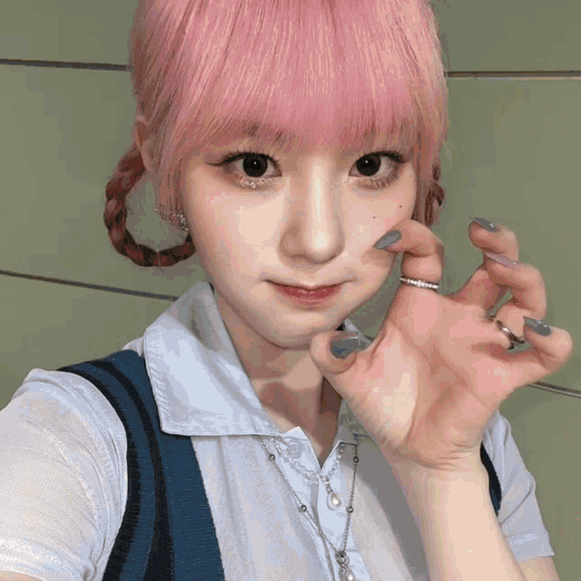 a girl with pink hair is wearing a white shirt and a blue vest