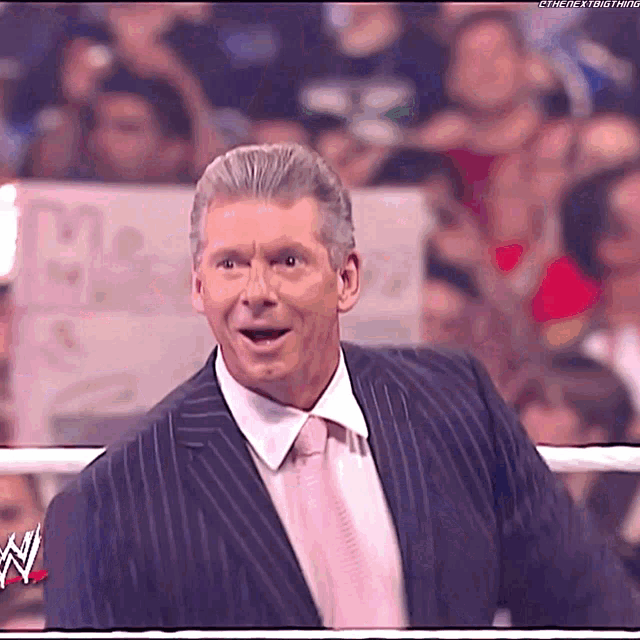 a man in a suit and tie stands in front of a crowd with a w logo