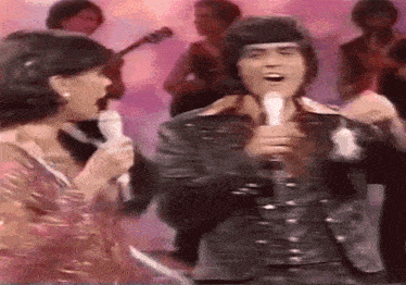 a man and a woman singing into microphones on a stage