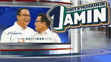 two men are laughing in front of a sign that says 1 amin