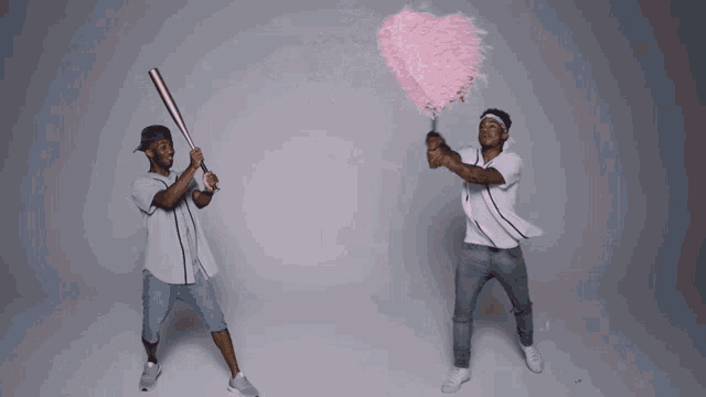 two men holding baseball bats and a pink heart shaped confetti cannon
