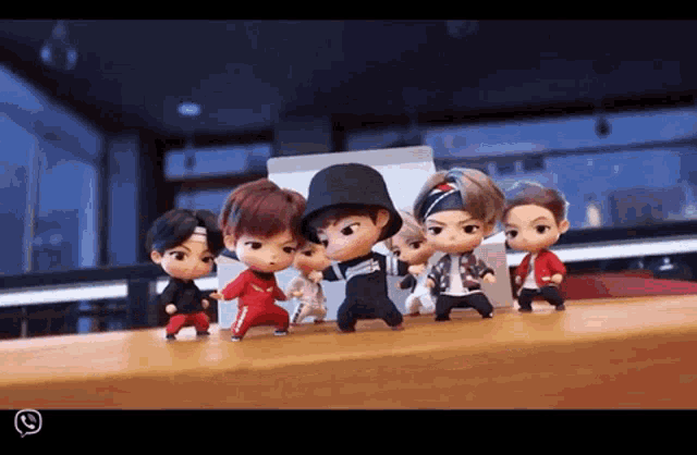 a group of dolls are standing on a table and one of them is wearing a hat