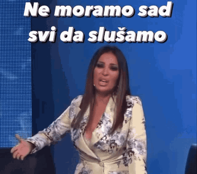 a woman in a floral dress is standing in front of a blue screen with the words `` ne moramo sad svi da slusamo '' .