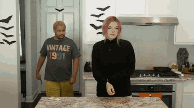 a man in a vintage 1991 shirt stands next to a woman in a kitchen