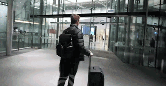 a man with a backpack and a suitcase walks through an airport