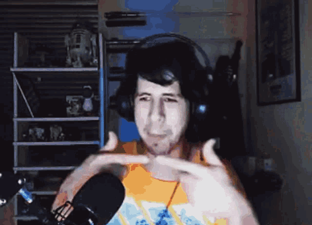 a man wearing headphones stands in front of a microphone making a funny face