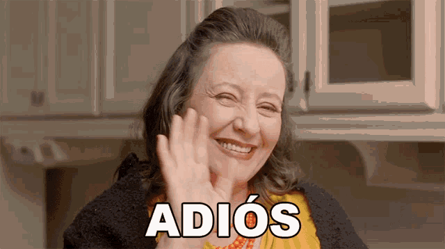 a woman smiles and waves her hand with the word adios behind her