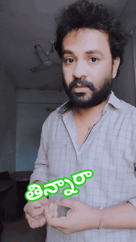 a man with a beard is wearing a shirt with a green sticker that says ' telugu '