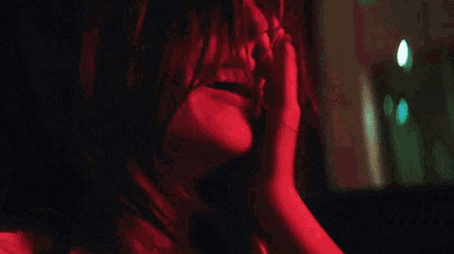 a close up of a woman 's face with red light behind her