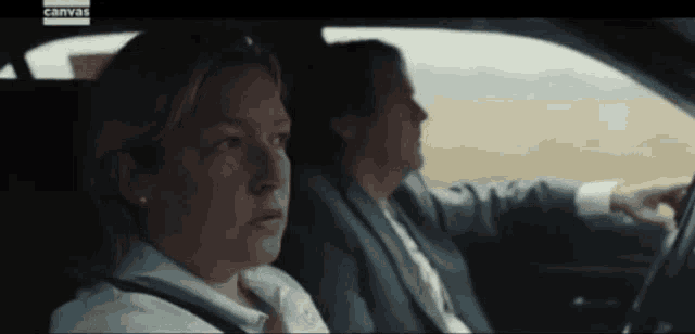 a man and a woman are sitting in a car with the word canvas on the bottom right
