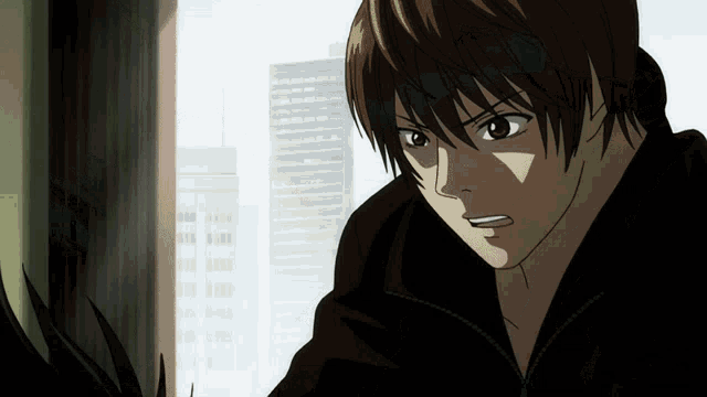 a man in a black jacket is looking out a window with a city in the background