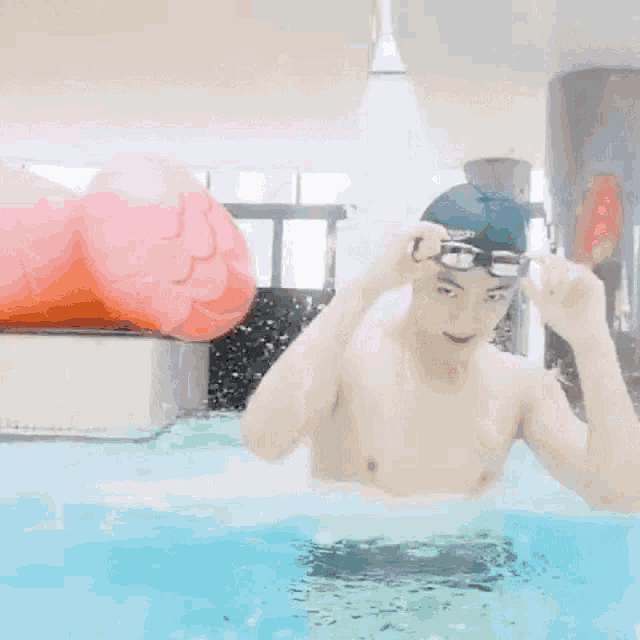 a shirtless man in a swimming pool wearing goggles and a swim cap