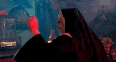 a woman dressed as a nun is dancing in a dark room .