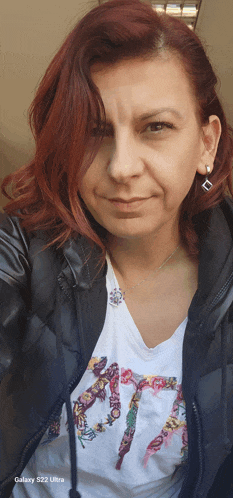 a woman with red hair is wearing a galaxy s22 ultra jacket