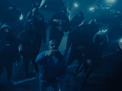 a man in a blue jacket stands in a crowd of people
