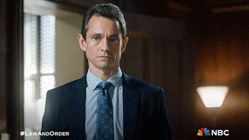 a man in a suit and tie stands in front of a sign that says law and order