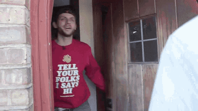 a man wearing a red sweater that says tell your folks i says hi