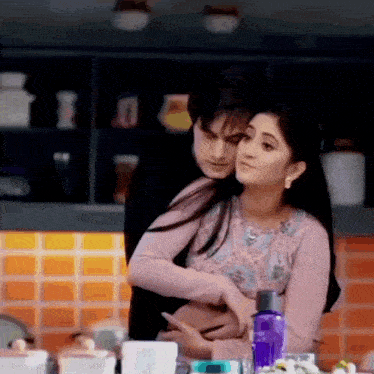a man and a woman are hugging each other in a kitchen while sitting at a table .