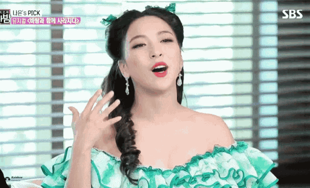 a woman in a green dress with sbs written on the bottom right