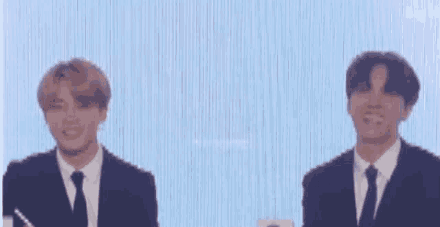 a couple of men in suits and ties are standing next to each other on a stage .