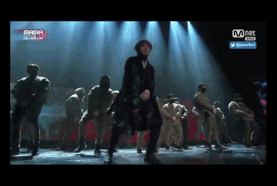 a group of people are dancing on a stage with a mnet logo in the corner