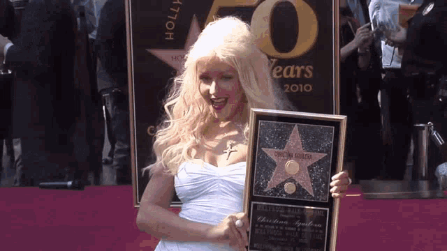 a woman in a white dress is holding a plaque that says 50 years 2010