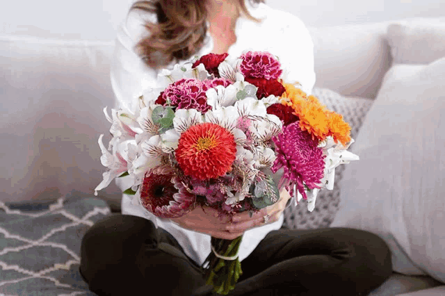 a woman is holding a bouquet of flowers in her lap