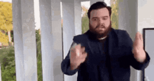 a man with a beard is making a funny face while standing in front of a balcony .