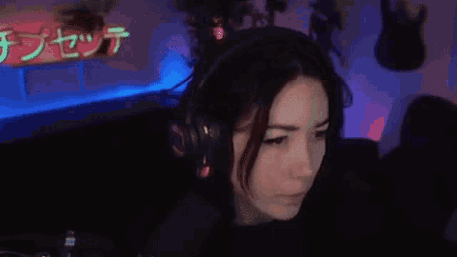 a woman wearing headphones and a microphone is sitting in front of a computer screen .