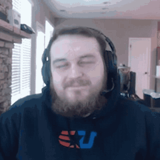 a man with a beard wearing headphones and a sweatshirt that says sxu