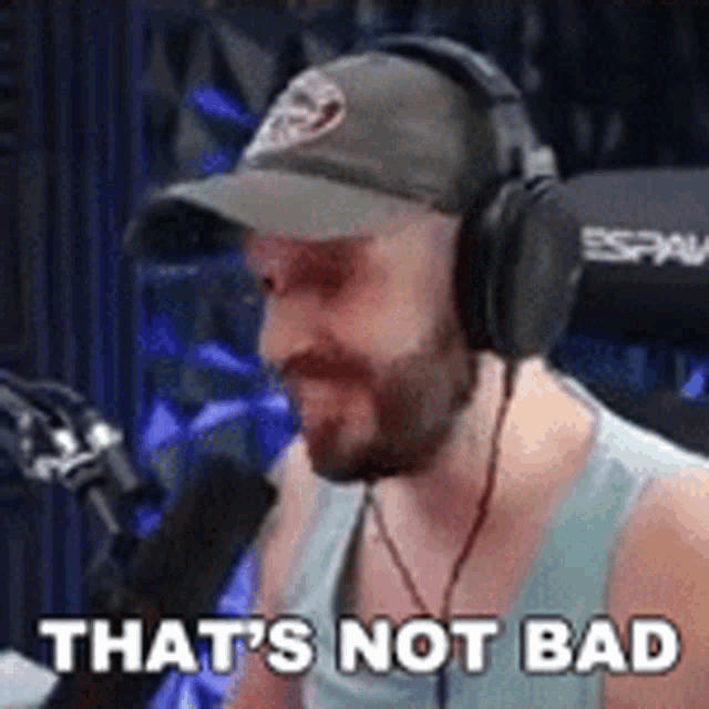 a man wearing headphones and a hat is sitting in front of a microphone .