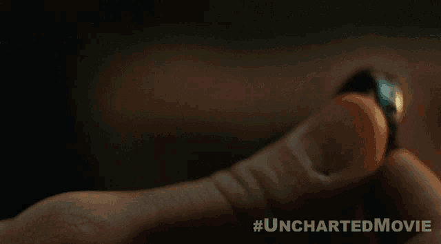 a close up of a person holding a ring with the hashtag #uncharteredmovie on the bottom