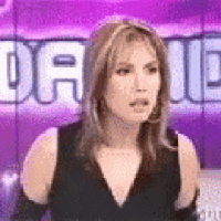 a woman in a black dress is standing in front of a purple wall with the word dave written on it .