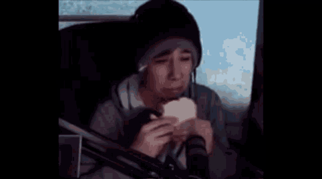 a man is sitting in front of a microphone and eating a sandwich .