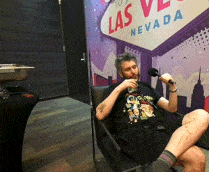 a man sits in a chair in front of a las vegas sign