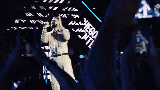 a man singing into a microphone in front of a sign that says " dicao "