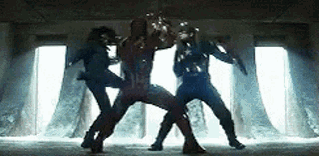 a group of superheros are fighting in a room .