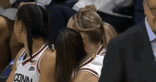 a female basketball player wearing a conn jersey talks to another player