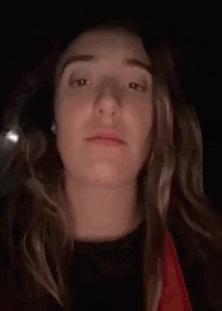 a woman with long blonde hair is making a funny face in a dark room .